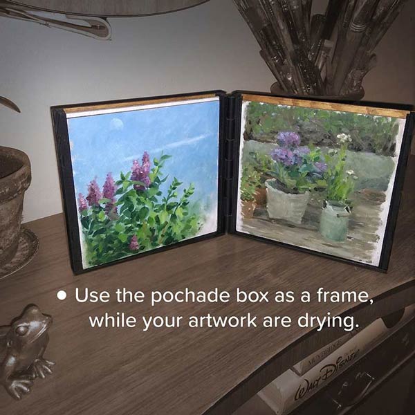 The pochade box is standing like a open book on a table in a home and it now contains two wet oil paintings and you can see that the box now act as a smart frame while the artworks is drying
